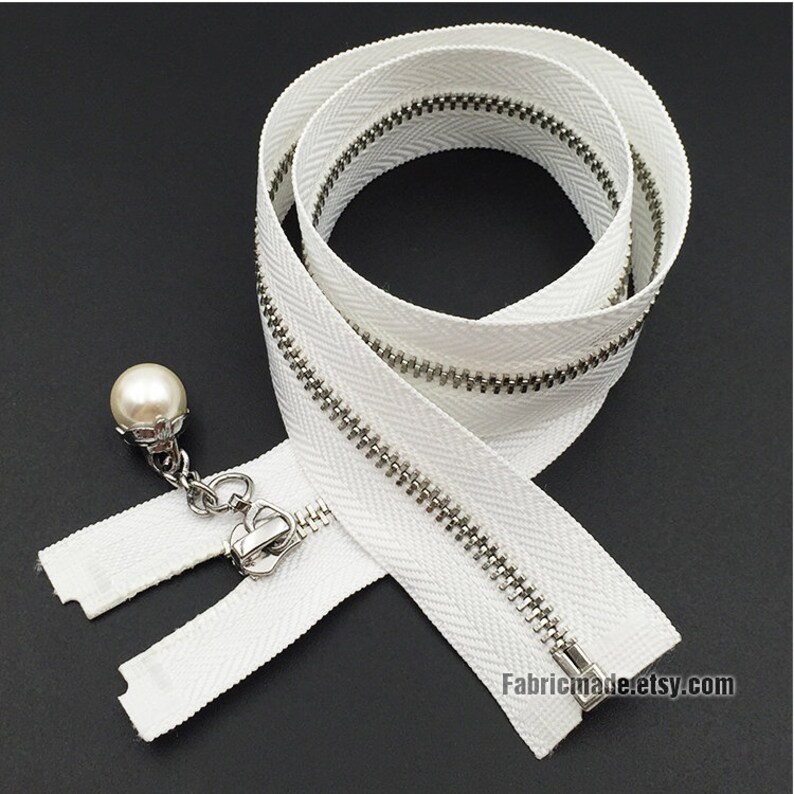 May include: White zipper with a silver metal slider and a pearl pull. The zipper is 22 inches long and has a herringbone pattern.
