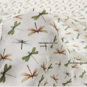 May include: White fabric with a repeating pattern of brown and green dragonflies. The fabric has the text "Fabricmade.etsy.com" printed on it.