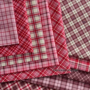 May include: A stack of red and white plaid fabric with a pink and white plaid fabric on top. The fabric is folded in a way that shows the different patterns. The text "Fabricmade.etsy.com" is visible at the bottom of the image.