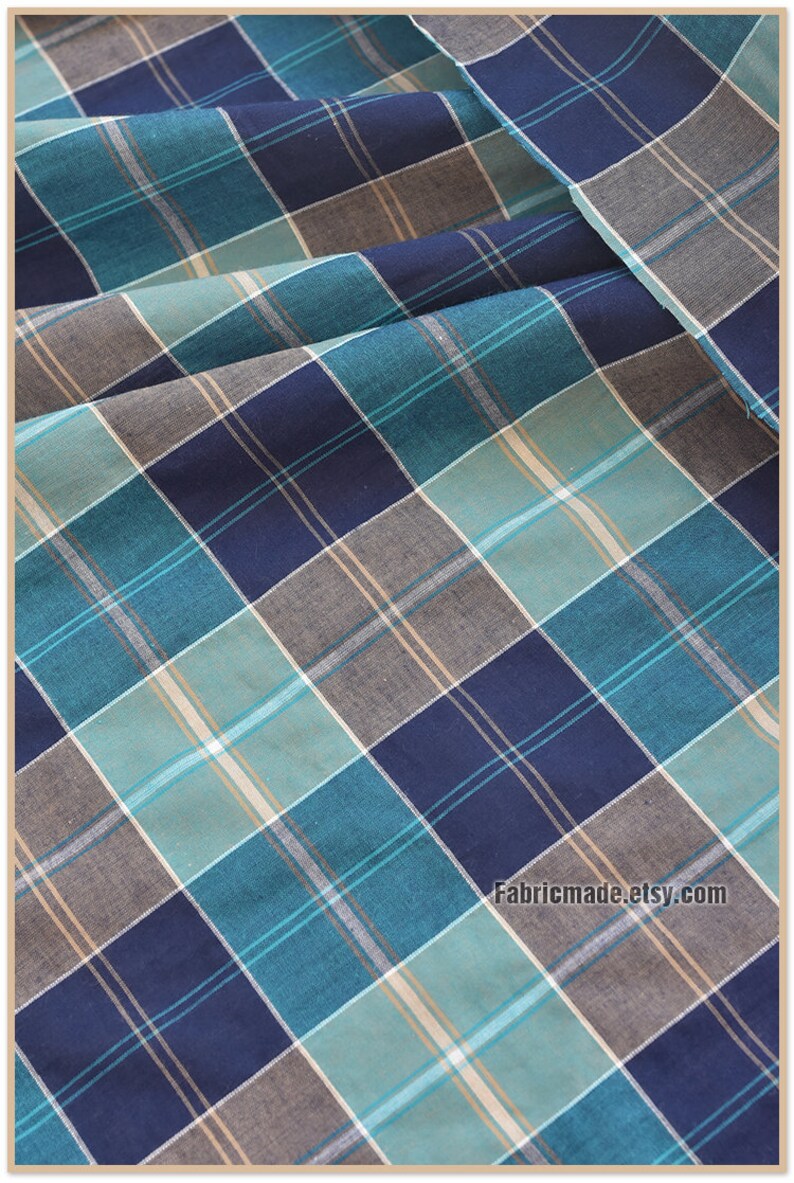 May include: Blue, teal, and beige plaid fabric. The fabric has a woven texture and is perfect for sewing projects.