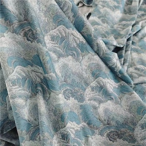 May include: A fabric with a repeating pattern of stylized ocean waves in shades of blue and white. The design features swirling water and cresting waves, creating a dynamic and textured appearance. The fabric is folded, showing the pattern's continuity.