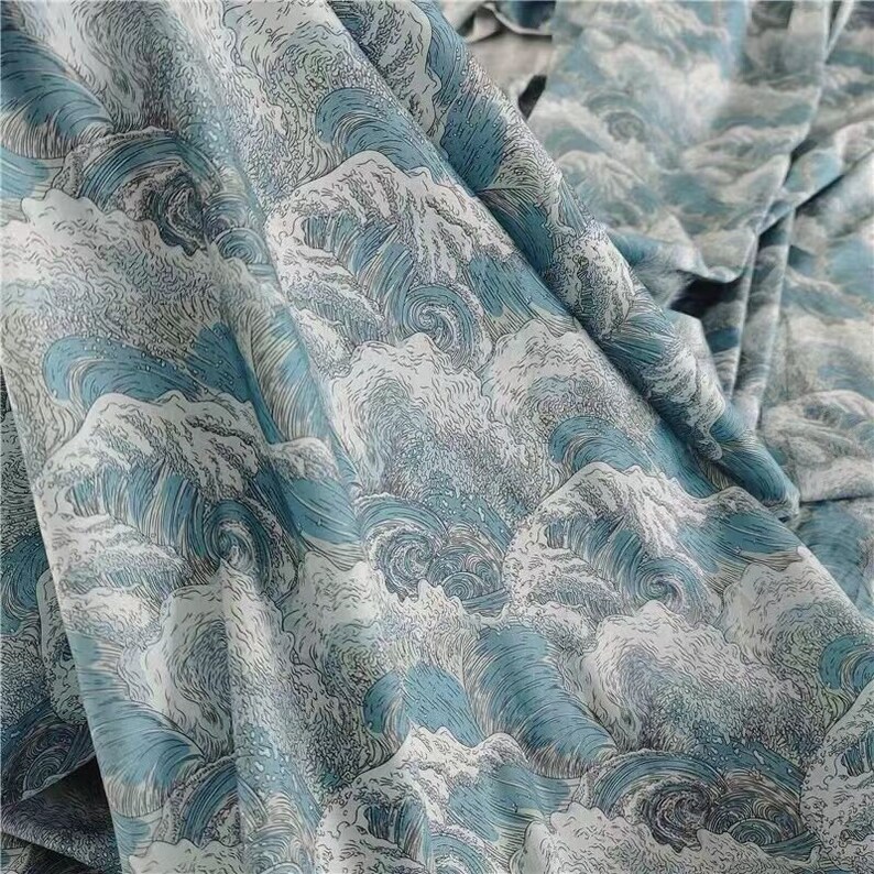 May include: A fabric with a repeating pattern of stylized ocean waves in shades of blue and white. The design features swirling water and cresting waves, creating a dynamic and textured appearance. The fabric is folded, showing the pattern's continuity.