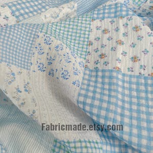 May include: Close-up of a patchwork fabric with various patterns. The fabric features squares of light blue gingham, floral prints, and white textured sections. The Etsy shop name "Fabricmade.etsy.com" is visible.