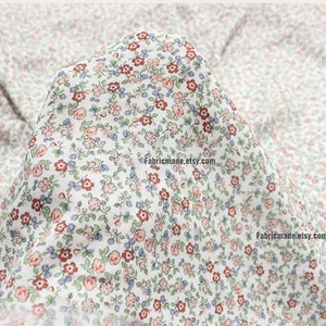 Peut inclure: Tissu en coton blanc avec un imprim&eacute; floral &agrave; petite &eacute;chelle dans des tons de rouge, rose, bleu et vert.