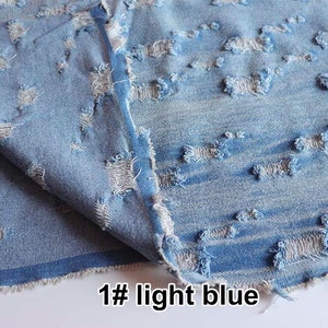 May include: Light blue denim fabric with a distressed, ripped look. The fabric has a horizontal pattern of small holes and frayed edges.