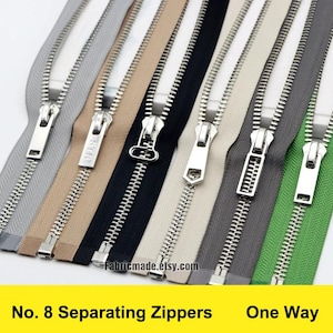 Puede incluir: Un conjunto de ocho cremalleras separables en varios colores, incluyendo plata, beige, negro, blanco, gris y verde. Las cremalleras son todas de una sola vía y tienen un acabado plateado. Las cremalleras están etiquetadas como "No. 8 Separating Zippers One Way".