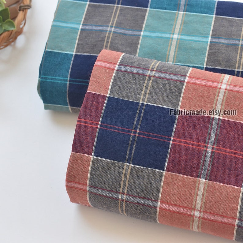 May include: Two pieces of plaid fabric, one in teal and gray, and the other in red, navy, and gray. The fabric is folded and the edges are visible. The fabric is available for purchase on the website Fabricmade.etsy.com.