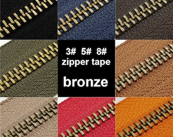 May include: Close-up of six zipper tapes in different colors with bronze zipper teeth. The tapes are labeled "3# 5# 8# zipper tape bronze".