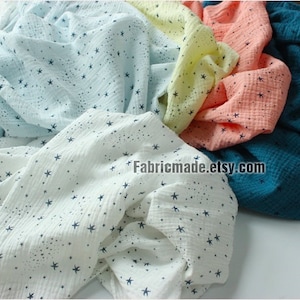 May include: Assortment of soft, textured fabric in various colors, including white, light blue, yellow, peach, and teal. Each fabric is adorned with a pattern of small, dark blue stars. The Etsy shop name "Fabricmade.etsy.com" is visible.