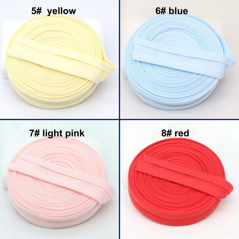 May include: Four spools of fabric trim in yellow, blue, light pink, and red. Each spool is labeled with a number and color name. The trim is folded over and appears to be made of a soft, flexible material.