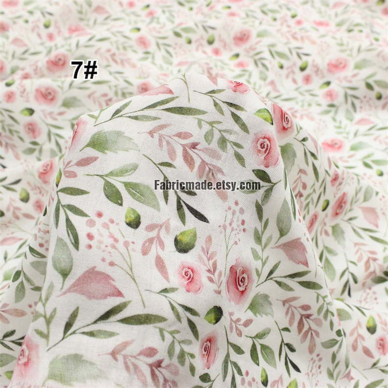 May include: White cotton fabric with a delicate floral pattern featuring pink roses and green leaves. The fabric has a watercolour effect and is perfect for crafting projects. The text "7#" is visible in the top left corner of the image.