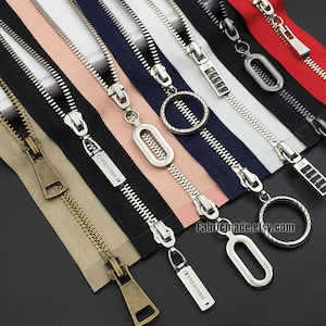 May include: Assortment of zipper pulls in various colours and styles, including silver, gold, and black. Some pulls feature a decorative design, such as a circle or a rectangle. The text "Fabricmade.etsy.com" is visible in the bottom right corner of the image.