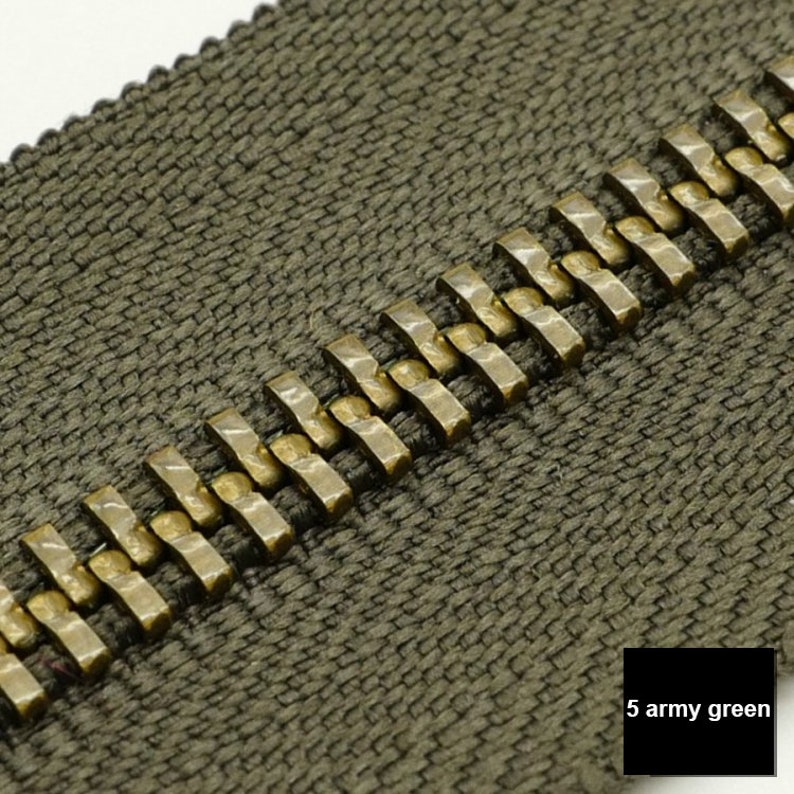 May include: Close-up of a zipper with a green fabric tape and gold metal teeth. The zipper is labeled "5 army green".
