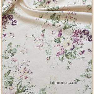 Puede incluir: Tela blanca con estampado floral con flores rosas, moradas y verdes. La tela tiene una textura sutil y un drapeado suave y fluido.