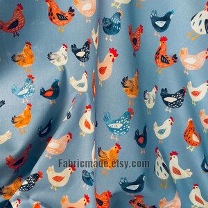 May include: A light blue fabric featuring a repeating pattern of chickens in various colors including orange, white, black, and blue. The chickens are depicted in different poses and sizes, scattered across the surface of the material.