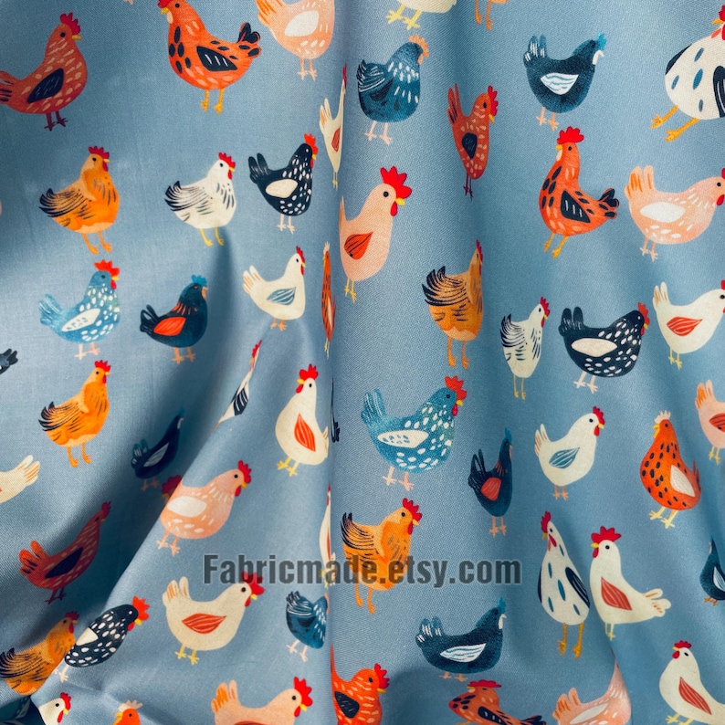 May include: A light blue fabric featuring a repeating pattern of chickens in various colors including orange, white, black, and blue. The chickens are depicted in different poses and sizes, scattered across the surface of the material.