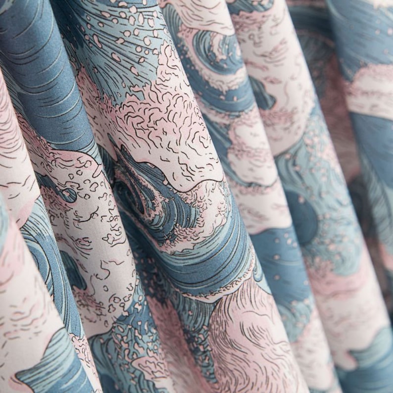 May include: Close-up of fabric with a repeating wave pattern in shades of blue, pink, and white. The design resembles a traditional Japanese woodblock print, with stylized waves and foam. The fabric is folded, creating depth and texture.