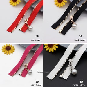 May include: Four different zipper tapes with metal sliders and pearl charms. The zippers are red with gold hardware, black with gold hardware, pink with gold hardware, and white with silver hardware.