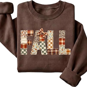 Peut inclure: Un sweat-shirt à manches longues marron foncé avec le mot FALL imprimé sur la poitrine. Les lettres sont composées de divers motifs en patchwork, notamment des imprimés léopard, à carreaux et floraux, avec un petit nœud sur la lettre A.