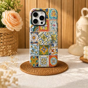 Peut inclure: Une coque de smartphone arborant un motif de carreaux méditerranéens multicolores et vibrants, avec des détails floraux et géométriques complexes. La coque comprend une poignée circulaire rétractable au centre, assortie au motif.