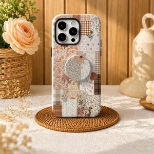 Può includere: Una custodia per smartphone con un design a collage a più motivi nei toni del beige, marrone e crema. Il motivo include disegni floreali, quadretti vichy e forme astratte. Un supporto circolare pieghevole è fissato al centro del retro.