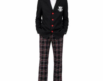 May include: A black blazer with four bright red buttons and a white crest patch on the chest, worn over a white mock neck shirt. The outfit includes black trousers featuring a white and red plaid pattern and black leather shoes.