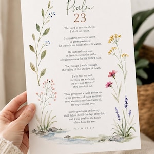 May include: A white rectangular print featuring the text of Psalm 23 in black font. The design is decorated with watercolour illustrations of green leafy stems, small blue berries, yellow wildflowers, pink blossoms, and purple lavender sprigs.