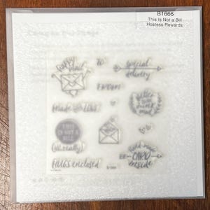 Puede incluir: Un juego de sellos de fotopolímero transparente etiquetado B1666 This Is Not a Bill Hostess Rewards. La hoja presenta varios diseños que incluyen sobres, corazones y texto como Happy Mail, Special Delivery, Made with Love y HUGS enclosed.
