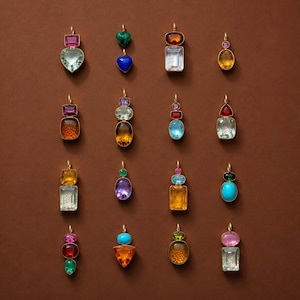 Può includere: Una collezione di sedici pendenti color oro con varie pietre preziose sfaccettate multicolori in forme diverse tra cui cuori, ovali, rettangoli e cerchi, ciascuno sospeso a un piccolo anello dorato per l'attacco a una catenina.