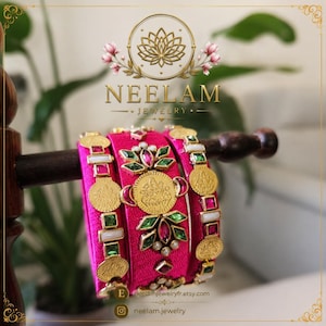 Pode incluir: Três pulseiras fúcsia vibrantes com detalhes em metal dourado, pingentes circulares tipo moeda e pedras facetadas verdes e rosas incrustadas. A pulseira central exibe um medalhão dourado. O texto NEELAM JEWELRY está visível acima.