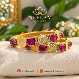 May include: Two gold-tone bangles featuring alternating round embossed coin-like discs and rectangular fuchsia-colored stones framed by small clear crystals. The jewelry is branded with the text NEELAM JEWELRY and social media handles.