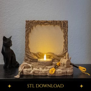 Op de afbeelding: Een beige, 3D-geprint vierkant frame met een textuur van een grot en een centraal rasterpaneel verlicht door een klein, warm LED-lampje. De basis heeft een steenachtig ontwerp met een schatkist, kristallen en gele borduurdraad.