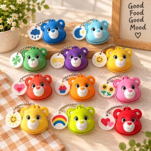 May include: A collection of eleven colourful bear-shaped keychains, each featuring a unique symbol on an attached circular charm. The bears come in various shades including blue, green, purple, yellow, red, orange, and pink, all with metal chains.
