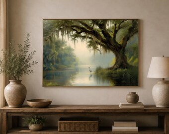 May include: A rectangular framed wall art print depicting a serene landscape with a large moss-draped tree overhanging a calm river. A single white heron stands near the water's edge, reflecting in the surface. The scene features soft green and brown tones.
