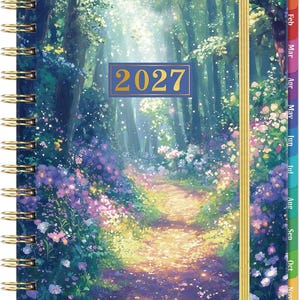 May include: A spiral-bound planner for 2027 featuring a vibrant forest scene with a sunlit path, purple and yellow wildflowers, and tall trees. The cover includes a gold elastic band and colorful monthly tabs along the right edge for organization.