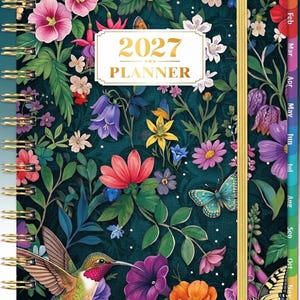 May include: A 2027 planner with a dark teal background featuring a vibrant floral pattern, butterflies, and a hummingbird. The planner has gold-colored spiral binding, a gold elastic closure, and monthly tabs along the right edge of the cover.