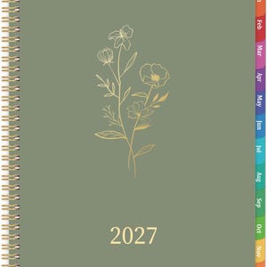 May include: A sage green spiral-bound planner for the year 2027. The front cover features a gold-colored line art illustration of wildflowers in the center and the year 2027 printed in gold at the bottom. It includes colorful monthly tabs.
