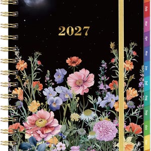 May include: A 2027 spiral-bound planner with a black cover featuring a night sky with a moon and stars above a colorful field of various flowers. The planner includes a gold elastic closure and monthly tabbed dividers labeled Jan through Dec.