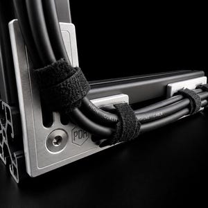 May include: A brushed silver metal cable management bracket featuring a hexagonal logo with the letters PDH and a circular bolt. Black cables are secured to the bracket with black hook-and-loop straps. The cables are labelled High Quality Microphone Cable.