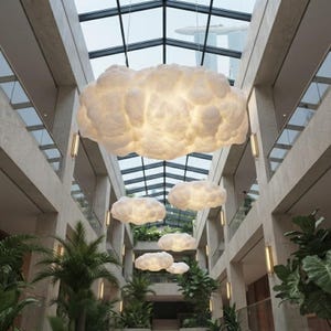 May include: A series of suspended cloud-shaped pendant lights with a soft, diffused white glow. These sculptural light fixtures are arranged in a vertical line, featuring a textured, organic surface that mimics the appearance of cumulus clouds.
