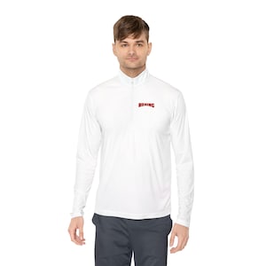Könnte beinhalten: Ein weißes Langarm-Shirt mit kurzem Reißverschluss am Kragen und dem Wort BOXING in roten Großbuchstaben auf der linken Brustseite. Das Kleidungsstück verfügt über einen Stehkragen mit vertikalem Reißverschluss und lange Ärmel.