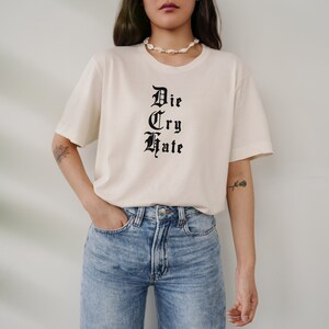 May include: A white t-shirt with black text that reads "Die Cry Hate" in a gothic font.