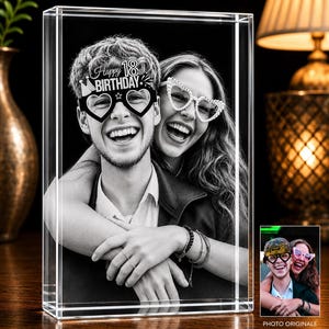 Peut inclure: Un bloc de verre rectangulaire présentant une photographie gravée au laser en noir et blanc de deux personnes s'enlaçant. La personne au premier plan porte des lunettes en forme de cœur avec le texte Happy 18th Birthday, l'autre des lunettes perlées.