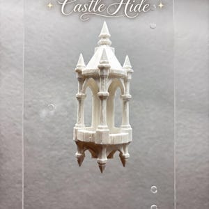 May include: A clear rectangular acrylic plaque featuring the white text Castle Hide with star icons. Attached to the centre is a white 3D-printed architectural structure resembling a small tower or gazebo with pointed spires and arched openings.