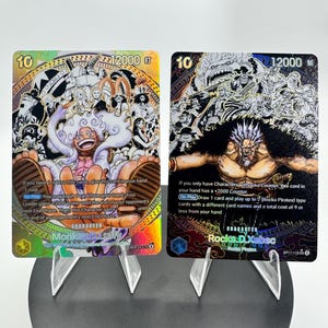 Può includere: Due carte collezionabili One Piece raffiguranti Monkey D. Luffy e Rocks D. Xebec. Entrambe le carte hanno un costo di 10, una potenza di 12000 e illustrazioni dettagliate. La carta di Luffy ha una finitura in lamina d'oro, quella di Xebec un design scuro e testurizzato.