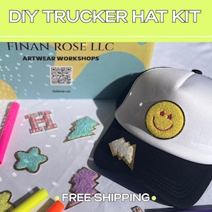 May include: A DIY trucker hat kit featuring a white and black trucker hat with a yellow smiley face patch. The kit includes various colorful patches shaped like lightning bolts, stars, and letters, along with several markers for customization.
