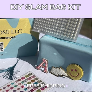 May include: A DIY glam bag kit featuring a light blue zippered pouch, a sheet of white pearl stickers, a sheet of multi-colored gem stickers, and three patches including a pink letter A, a white lightning bolt, and a yellow smiley face.