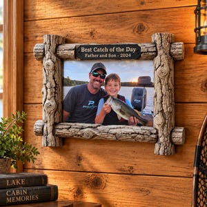 May include: A rectangular photo frame with a textured, faux-log border featuring a dark plaque at the top with the engraved text "Best Catch of the Day" and "Father and Son - 2024". The frame holds a photograph of two people holding a fish on a boat.