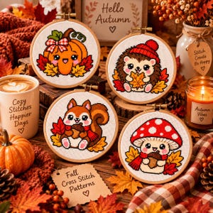 Puede incluir: Cuatro bastidores de bordado circulares de madera con diseños de punto de cruz de una calabaza naranja, un erizo con gorro rojo, una ardilla con una bellota y una seta con sombrero rojo, rodeados de hojas de otoño y decoración otoñal.