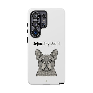 Può includere: Una cover per smartphone bianca con una grafica nera di un Bulldog Francese con intricati motivi in stile mandala. Il testo "Defined by Detail." è stampato in nero sopra l'illustrazione del cane. La cover presenta un modulo fotocamera nero.